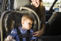 Mujer con hijo pequeño sentado en el coche - foto de stock