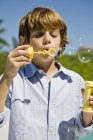 Boy blowing bubbles with bubble wand outdoors — Stock Photo