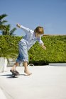 Маленький хлопчик скейтбординг в літньому саду — стокове фото