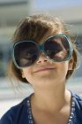 Retrato de menina sorridente usando óculos de sol ao ar livre — Fotografia de Stock