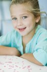Porträt eines lächelnden kleinen Mädchens am Schreibtisch — Stockfoto