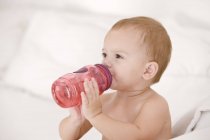 Baby girl drinking water from baby bottle — Stock Photo