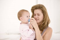 Mulher segurando chupeta na boca da filha bebê — Fotografia de Stock