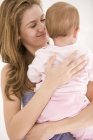 Close-up of happy woman holding baby daughter — Stock Photo