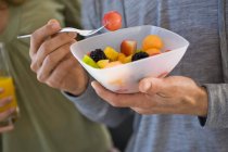 Close-up of male hands holding bowl of fruit salad — Stock Photo