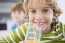Портрет усміхненого маленького хлопчика, що тримає склянку соку — стокове фото