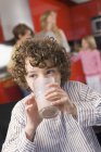 Ritratto di ragazzo che beve latte da vetro in cucina — Foto stock