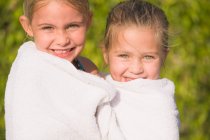 Портрет двох дівчат, загорнутих в рушник і усміхнених — стокове фото