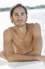 Portrait of young shirtless man relaxing at lake — Stock Photo