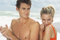 Romantique jeune couple regardant loin sur la plage — Photo de stock