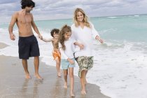 Famille heureuse marchant sur la plage de sable — Photo de stock