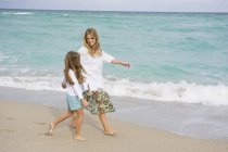 Donna che cammina sulla spiaggia sabbiosa con figlia — Foto stock