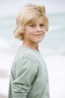 Portrait de garçon blond debout sur la plage — Photo de stock