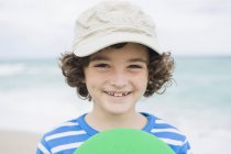 Мальчик играет с пластиковым фрисби на пляже — стоковое фото