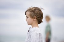 Вид збоку маленького хлопчика, який думає на розмитому фоні — стокове фото