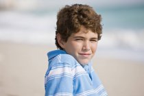 Портрет усміхненого хлопчика, що сидить на пляжі — стокове фото