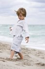 Kleiner Junge spielt mit Sand am Strand — Stockfoto
