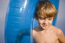 Усміхнений маленький хлопчик тримає блакитне надувне кільце — стокове фото