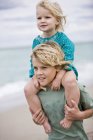 Хлопчик носить сестру на плечах на пляжі — стокове фото