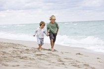 Cheerful boys running on sandy beach — Stock Photo