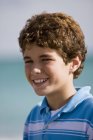 Porträt eines lockigen Jungen, der im Freien lächelt — Stockfoto