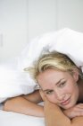 Primo piano di donna sognante sdraiata sul letto sotto il piumone e sorridente — Foto stock