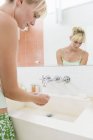 Loira jovem mulher lavar as mãos no banheiro — Fotografia de Stock
