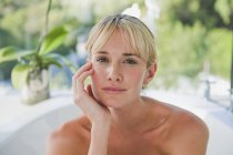 Porträt einer jungen blonden Frau in Badewanne mit Garten im Hintergrund — Stockfoto