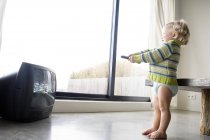 Pequeño niño sosteniendo TV control remoto en casa - foto de stock