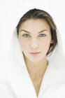 Portrait of serious young woman with blue eyes in bathrobe — Stock Photo