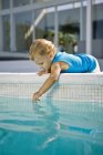 Baby boy playing with water in swimming pool — Stock Photo