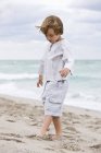 Продуманий маленький хлопчик грає на піщаному пляжі — стокове фото