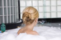 Задний вид блондинки, принимающей ванну с пеной — стоковое фото