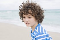 Nachdenklicher Junge mit lockigem Haar am Strand — Stockfoto