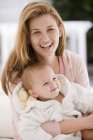 Portrait of smiling woman with baby daughter — Stock Photo
