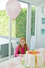 Chica pelirroja sentada en la mesa durante la fiesta de cumpleaños - foto de stock