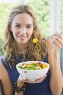 Портрет улыбающейся женщины, которая ест фруктовый салат — стоковое фото