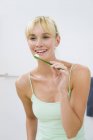 Sorridente giovane donna che tiene lo spazzolino in bagno — Foto stock