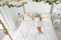Innocente bambina che dorme sul letto decorato con foglie — Foto stock