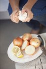 Primer plano de manos femeninas pelando verduras en el plato - foto de stock