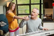 Uomo che canta e suona un pianoforte con sua figlia a casa — Foto stock