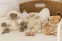 Gros plan de peluches mignonnes jouets sur le lit dans la chambre d'enfant — Photo de stock