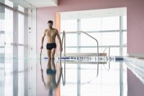 Alto atlético em pé na piscina — Fotografia de Stock
