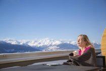 Femme buvant du café sur la terrasse avec vue sur les montagnes, Crans-Montana, Alpes suisses, Suisse — Photo de stock