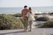 Счастливая пара, гуляющая по растительности на морском побережье — стоковое фото
