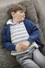 Расслабленный мальчик с закрытыми глазами лежит на пушистой подушке — стоковое фото