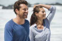 Feliz casal olhando para longe na praia — Fotografia de Stock