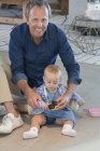 Портрет взрослого мужчины, играющего с маленькой дочкой на полу дома — стоковое фото