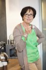 Sonriente mujer mayor bebiendo café en la cocina - foto de stock
