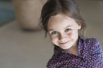 Портрет милої маленької дівчинки, яка посміхається в приміщенні — стокове фото